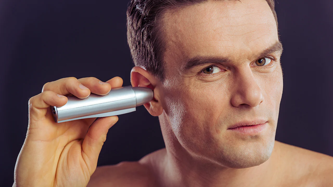 A man using an electric ear trimmer to remove ear hair